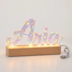 Star hologram acrylic letters spelling Aria on a wooden LED base