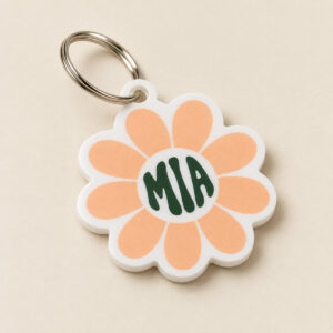 White acrylic daisy-shaped name tag printed with MIA in deep evergreen on a silver ring