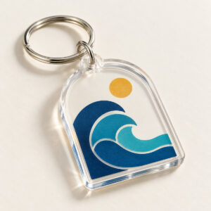 Clear arch-shaped acrylic tag printed with nested blue and turquoise ocean-wave arcs and a small ochre sun, on a silver ring