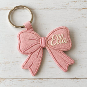 Pink bow-shaped canvas tag embroidered with the name Ella on a keyring