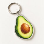 Avocado Pit Acrylic Keychain with an avocado half in leaf green with a warm brown pit and soft cream highlight