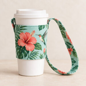 Hummingbird Cup Holder with Strap with a hummingbird beside a coral hibiscus flower with green leaves on a pale teal field