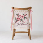 Cherry Blossom Lace Chair Banner with a cluster of cherry blossoms in deep rose pink and dark green with the words "Just Married" in dark plum below, kept clear of the lace trim