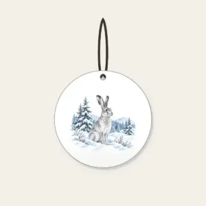 Hare in a Snowy Field with Pines Ceramic Ornament in white: A hare pauses in a snowy field among pines in white, grey and ice blue.
