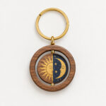 Sun and Moon Spinning Wood Keychain with a round wood piece with a spinning inner circle printed with a half sun and half moon in gold and navy