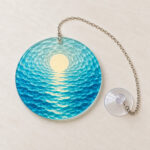 Ocean Ripple Suncatcher with layered concentric ripples in ocean blue and aqua with a small cream sun at the top