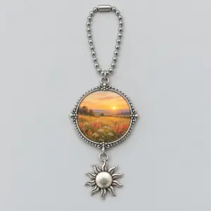 Round metal meadow-print photo charm with a dangling sun and bead chain