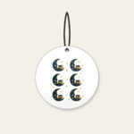 Crescent Moon with a Stack of Books Ceramic Ornament in white: A crescent moon holds a small stack of books among tiny stars in navy and gold.