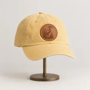 Engraved Heron Patch Dad Hat with an engraved heron standing in reeds on the patch, single tone