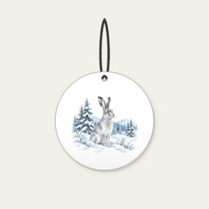 Hare in a Snowy Field with Pines Ceramic Ornament in white: A hare pauses in a snowy field among pines in white, grey and ice blue.