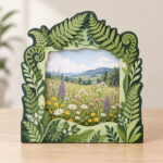Four-Tone Fern Layered Frame with a layered fern-leaf border in four tones of green around a central window that holds an original sample botanical picture of a meadow with wildflowers