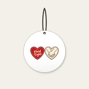 Hold Tight Heart and Hands Ceramic Ornament in white: A red dashed heart marked “Hold Tight” on one side and two clasped cream hands in brown on the other.
