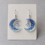 Pair of acrylic drop earrings in crescent and star shapes with constellation lines