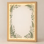 Terrarium Photo Frame Light Box with a printed border of succulents, ferns and tiny stones in green and warm grey around an empty photo area