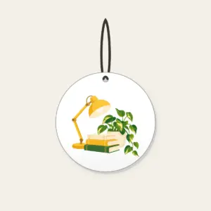 Lamplit Desk with Books and Fern Ceramic Ornament in white: A warm yellow desk lamp glows beside a stack of books and a potted plant in cream and green.