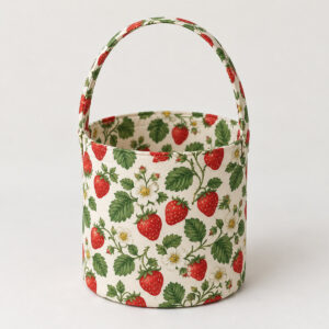 Strawberry Patch Fabric Basket with flat red strawberries, white blossoms and green leaves on cream fabric, cylindrical basket with bound rim and one arching fabric handle