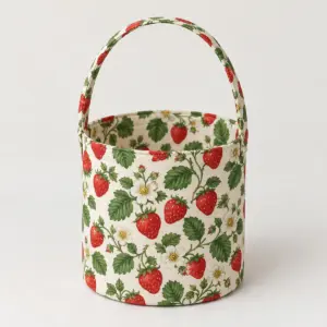 Strawberry Patch Fabric Basket with flat red strawberries, white blossoms and green leaves on cream fabric, cylindrical basket with bound rim and one arching fabric handle