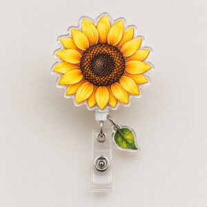 Sunflower Charm Badge Reel with a round sunflower-shaped reel face with yellow petals and a brown seed center, tiny green leaf charm hanging below
