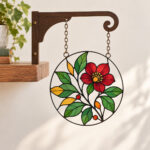 Garden Window Suncatcher Bookshelf Sign with round flat printed stained-glass-style illustration with jewel-tone sections of leaves and a flower in green, ruby and amber