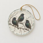 Starling Branch Glass Ornament with three starlings on a bare branch in charcoal and iridescent green on a pale ground
