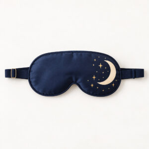 Crescent Moon Sleep Mask with a deep navy mask with a cream crescent moon and tiny gold stars near one edge