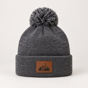 Cabin Patch Pom-Pom Beanie with small flat printed patch design on the cuff showing a cabin outline with a curl of chimney smoke