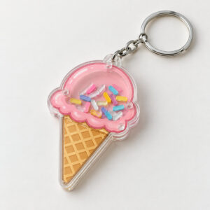 Ice Cream Cone Shaker Keychain with a cone with a pink scoop and cream waffle with a clear window of tiny sprinkles
