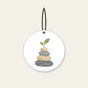 Cairn Stones with a Sprout Ceramic Ornament in white: Stacked cairn stones in grey and sand, topped with a tiny green sprout.