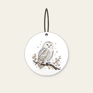 Snowy Owl in Snowfall Ceramic Ornament in white: A snowy owl on a branch in white, slate and amber with falling snowflakes.