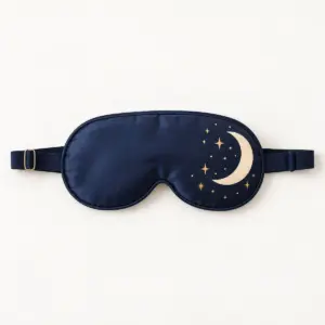 Crescent Moon Sleep Mask with a deep navy mask with a cream crescent moon and tiny gold stars near one edge