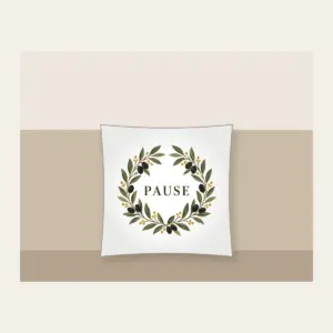 Olive Branch Wreath with PAUSE Pillow in white: An olive branch wreath with dark fruits and ochre dots circles the word PAUSE in simple deep green serif letters.